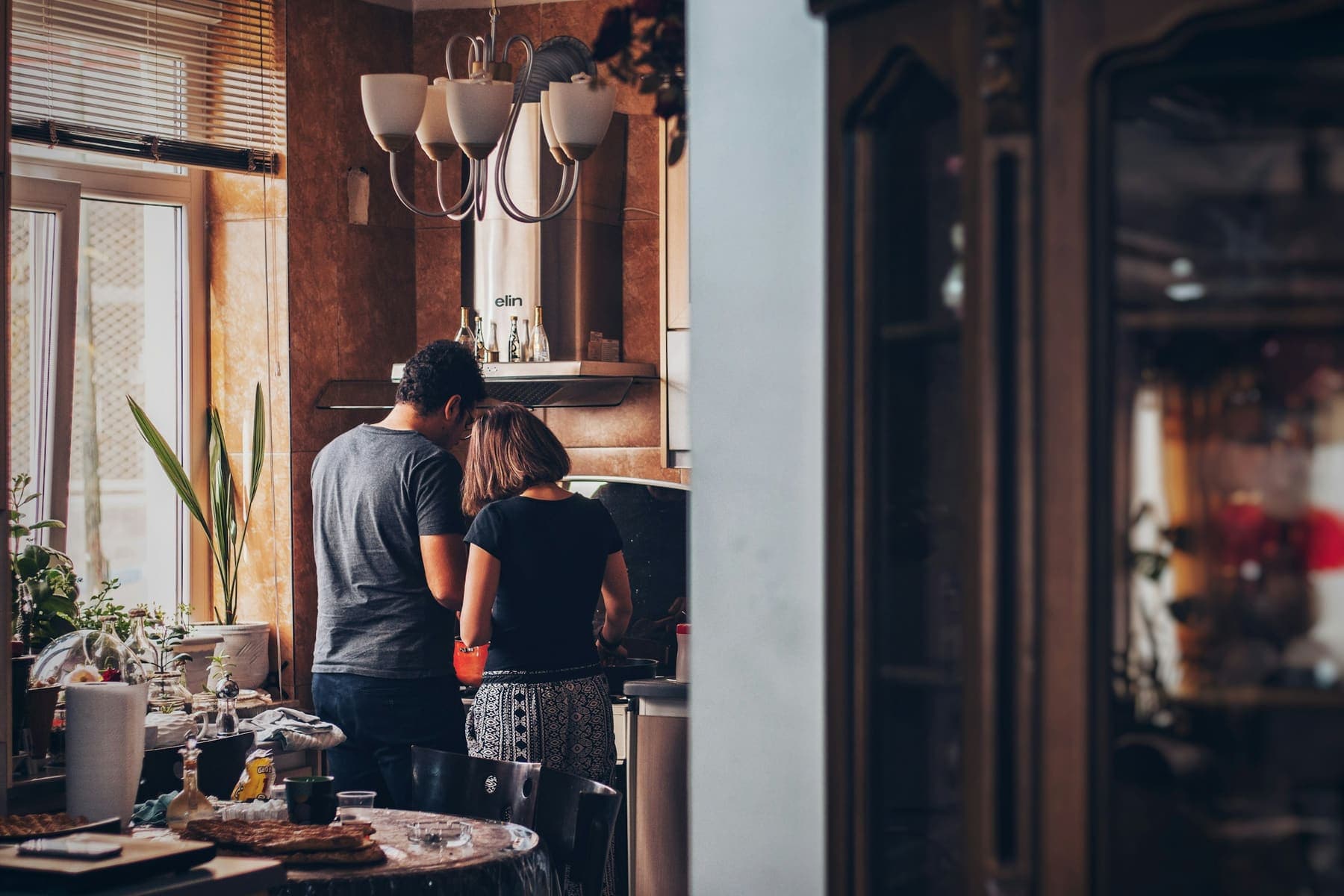 A couple cooking together in their kitchen, warm evening light